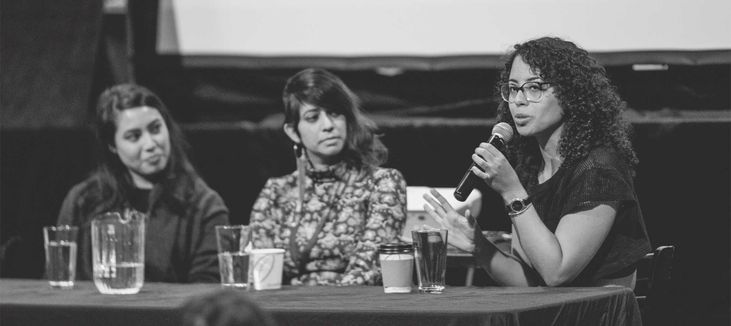 Three panelists seated at a table, one speaking into a microphone at ReFrame 2019