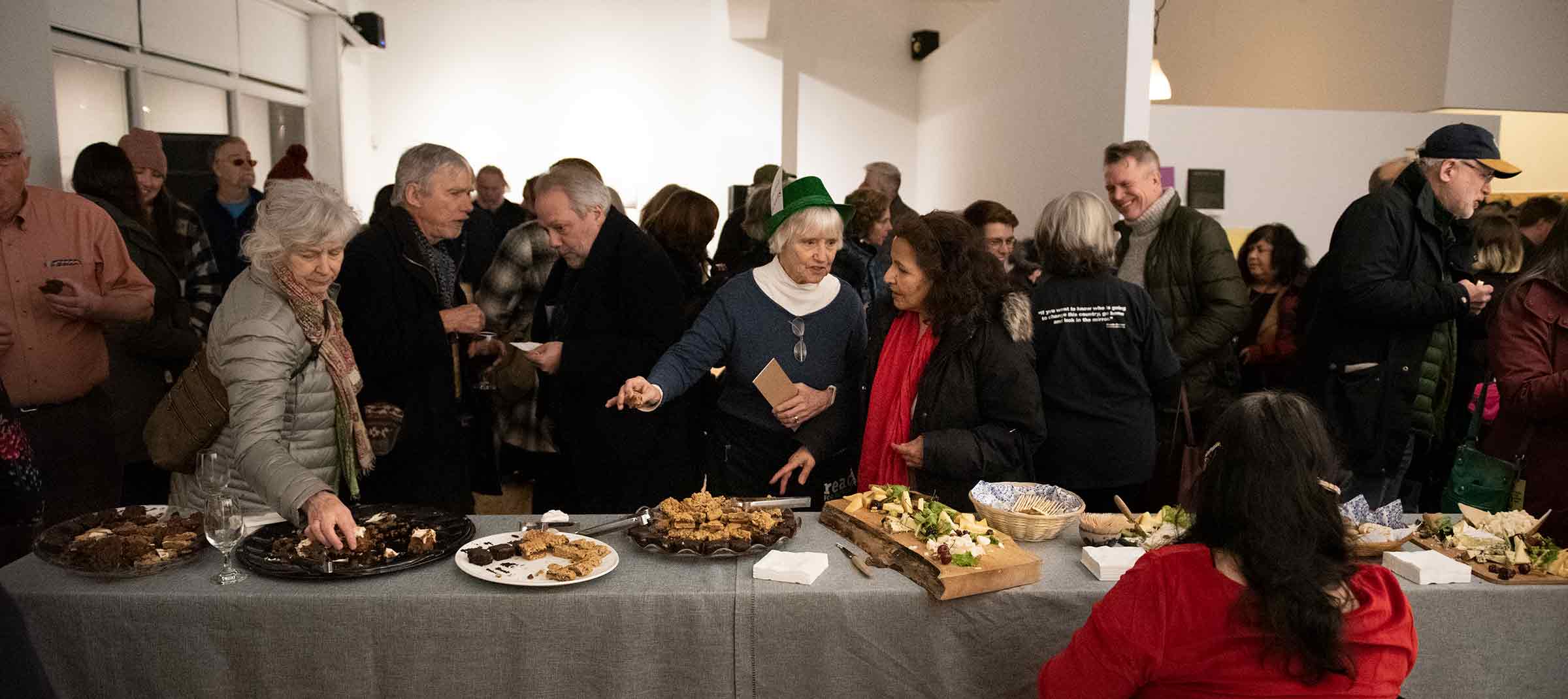 Wide shot of festival patrons gathered at the buffet table at the ReFrame Film Fete