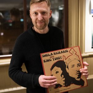 Filmmaker Chris Flanagan posing with a vinyl record at the screening of his film "Shella Record: A Reggae Mystery"