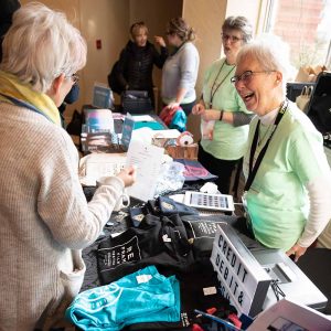 ReFrame volunteer laughing with patrons at the merchandise table