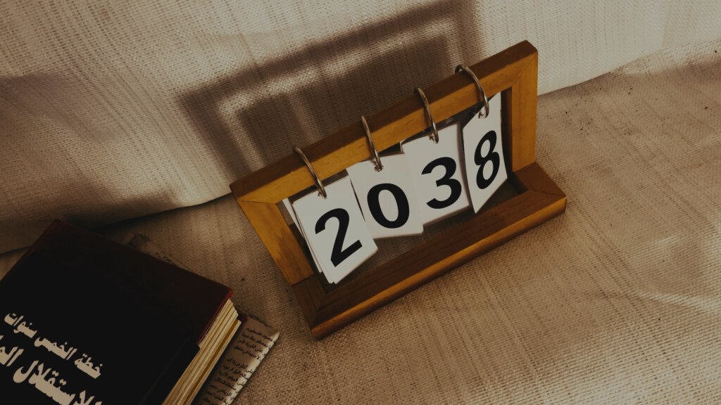 A wooden frame with flippable numbers reads "2038". It is set on the floor next to a small stack of books.