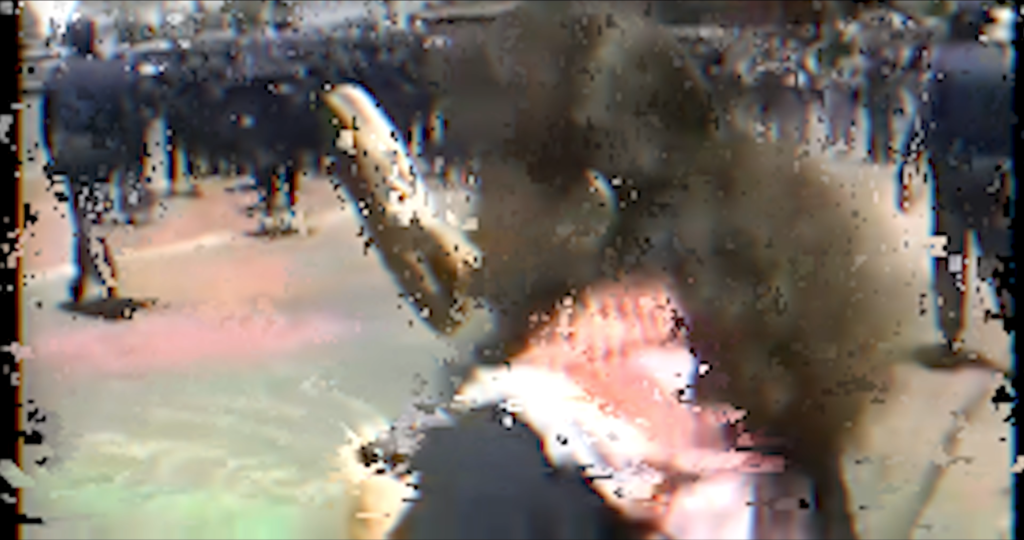 A glitchy image of a protester, possibly wearing a Keffiyeh. Many smaller figures line the background.