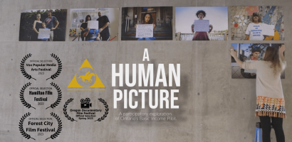 A promotional image for a documentary described as a participatory exploration of Ontario's Basic Income Pilot. The image features a wall with several photographs of individuals holding signs, and a person on a stepladder placing or adjusting one of the pictures. The wall also includes laurels indicating the film's selection for various festivals. Additionally, there's a symbol for the International Motion Picture Awards. The setting appears to be an exhibition or a public area.